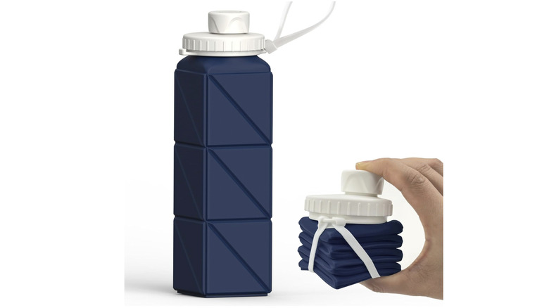 View of navy BEAUTAIL Collapsible Water Bottle, fully expanded on left side and collapsed in a person's hand on right side