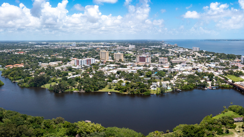 Aerial view of Melbourne, Florida and the surrounding suburbs with water and foliage in the foreground visible on a sunny day