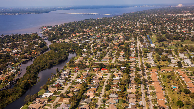 Aerial view of Fort Myers and suburbs in Southwest Florida on a sunny day with water in the background and typical suburban residential subdivisions visible