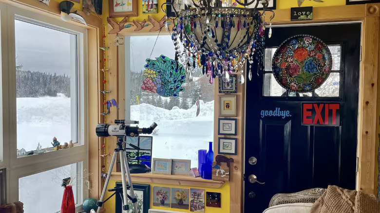 Bright yellow living room with telescope directed at snow