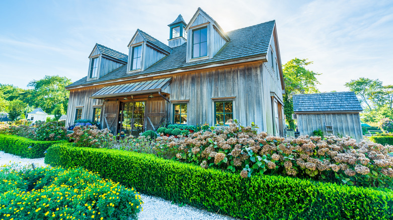Green hedges in front of a gray farmhouse at Beach Plum Farm
