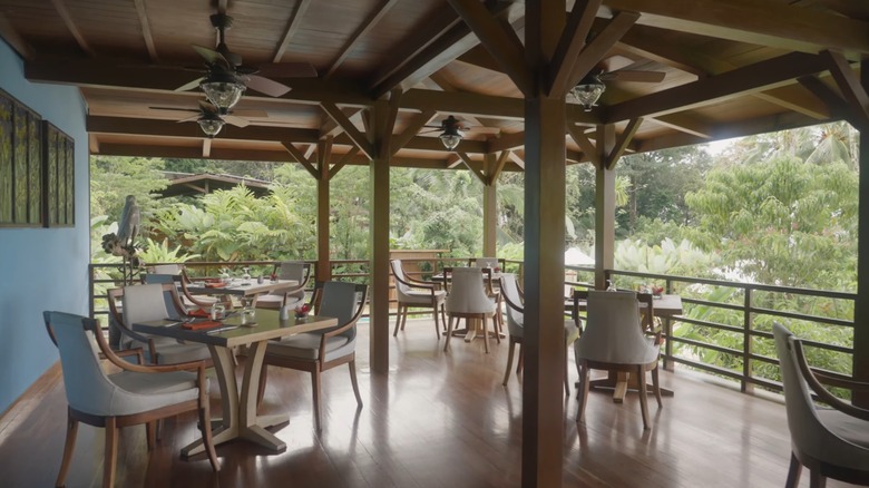 An open-air resort dining area with empty tables ready for food service