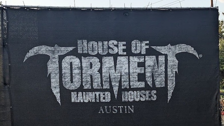 Black sign outside the House of Torment haunted house attraction in Texas