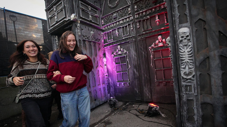 Two girls running from haunted house with skeletons on it