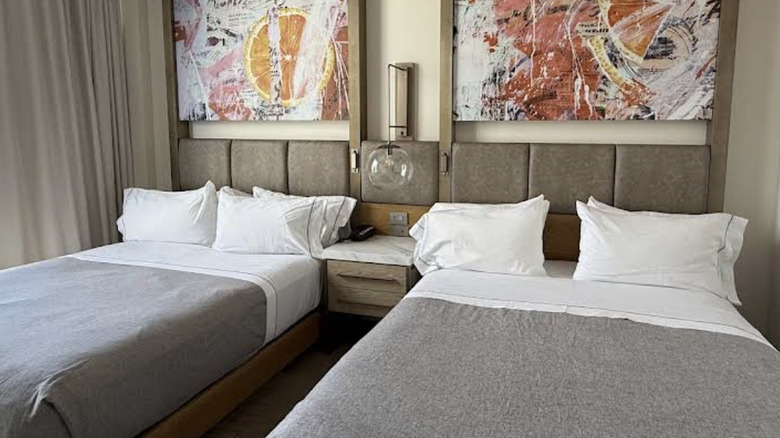 View of guest room with modern artwork and sleek beds with grey bedding at Canopy by Hilton hotel in West Palm Beach
