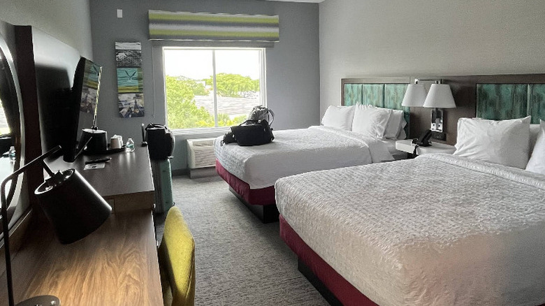Interior view of double room at Hampton Inn & Suites Miami Kendall with bright pops of color on grey walls and a view of foliage out of a large window