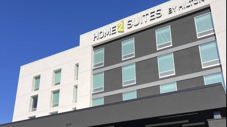 Exterior of modern Home2 Suites by Hilton Fort Walton Beach Eglin Air Force Base with signage visible and a blue sky in the background