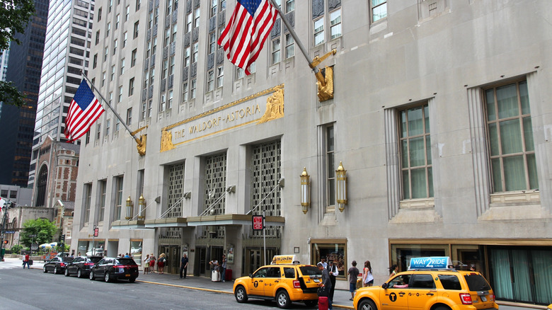 Yellow cabs and people outside the Art Deco facade of the iconic Waldorf Astoria New York