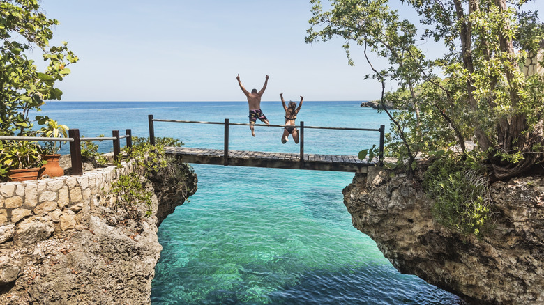 Couple on vacation jumping off a wooden bridge