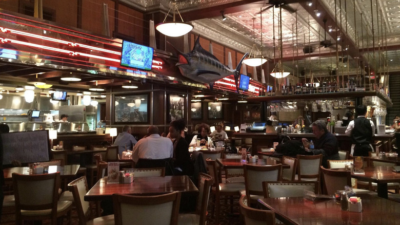 Warm restaurant interior with TVs, lights, and fish hanging