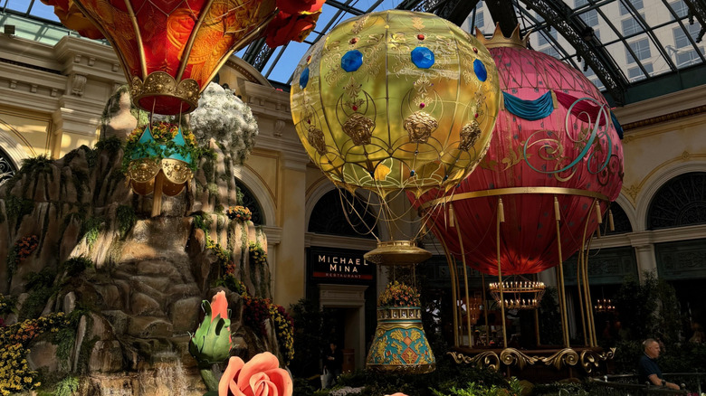 View of Bellagio gardens in the summer with over-the-top oversized hot air balloon display, with slight view of glass roof at the top of frame