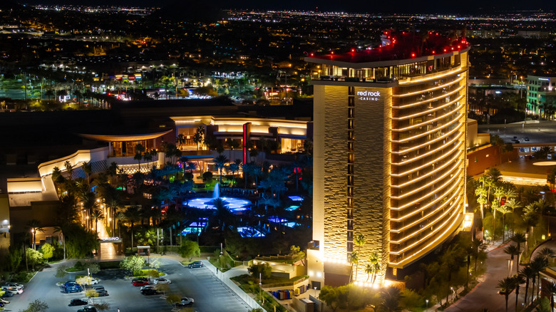 Nighttime aerial view of Red Rock Casino Resort and Spa in Las Vegas, Nevada, illuminated with golden lights and a glowing pool area