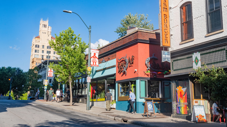 A few people walk by independent businesses along a downtown Asheville, North Carolina