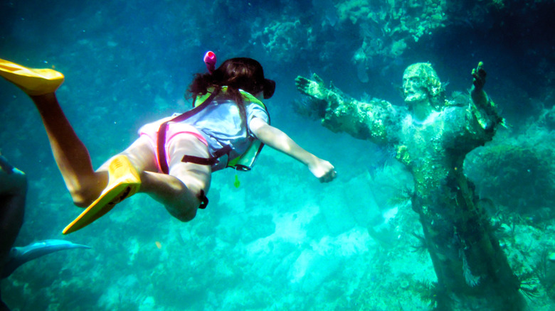 Underwater shot of a young girl snorkeling to the Christ of the Abyss Statue off Key Largo Florida