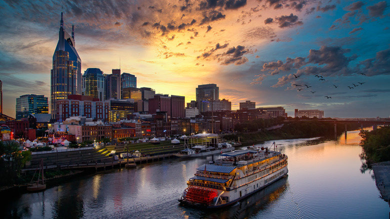 Cruise ship gliding on waters at sunset past a city skyline