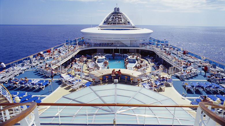 View of a lively sunlit cruise deck from top against the backdrop of a an endless blue ocean