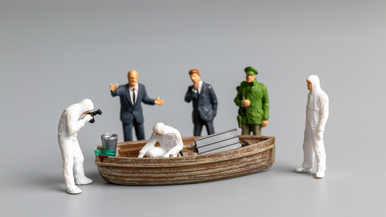 Miniature models of police, forensics, and detectives working on a boat, as part of a crime scene concept