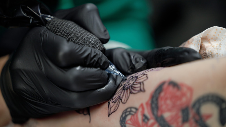 Close up of a tattoo artists' needle as they tattoo a person's arm