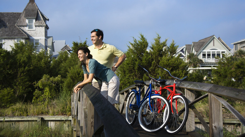 A couple with their blue and red bicycles take a break on a wooden bridge on Bald Head Island