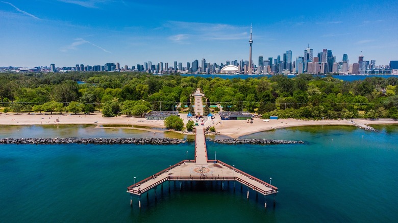 An aerial view of the Centre Island Pier with a green landscape carpeting the island and the Toronto skyline in the background