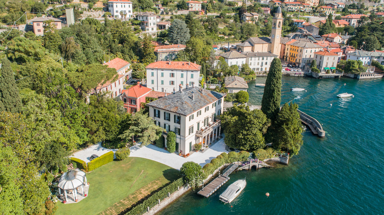 Aerial view of a lakeside villa, terraced gardens, cypress trees, and a private waterfront on Lake Como