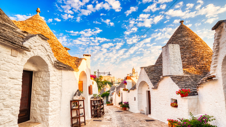 Narrow lane lined with white-washed stone huts with cone-shaped stone roofs in Puglia