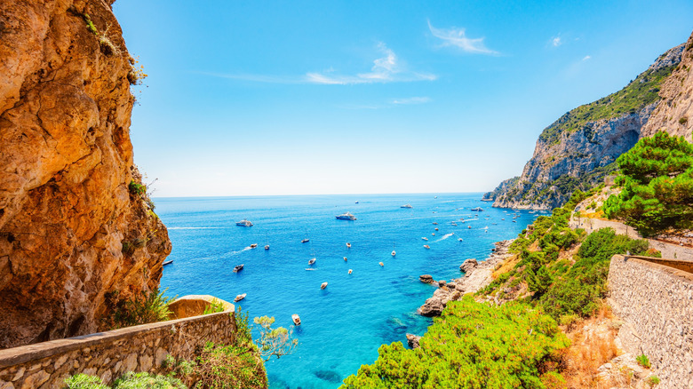 Rocky and mountaneous coast of Capri, turquoise waters dotted with boats