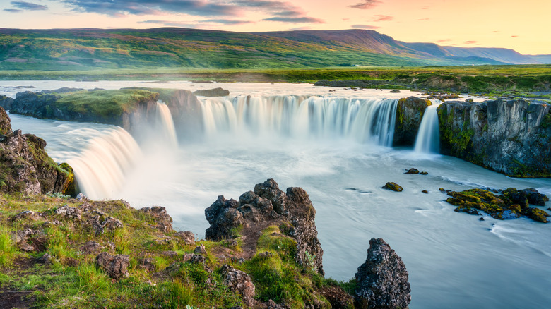 Majestic landscape of Godafoss waterfall flowing and colorful sunset sky on Skjalfandafljot river in northern Iceland