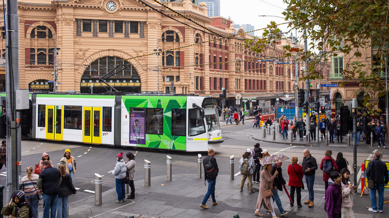 A view of Flinders Street Station in Melbourne Australia with pedestrians and trams.