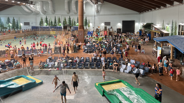 Visitors at indoor water park with wave pool, surf simulator, and seating at Great Wolf Lodge in Manteca, California
