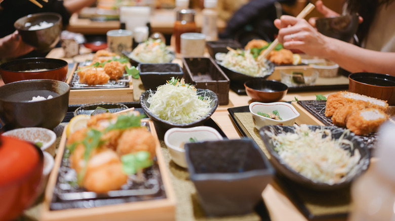 Close up of dinner table laden with traditional Japanese food and a Tonkatsu set