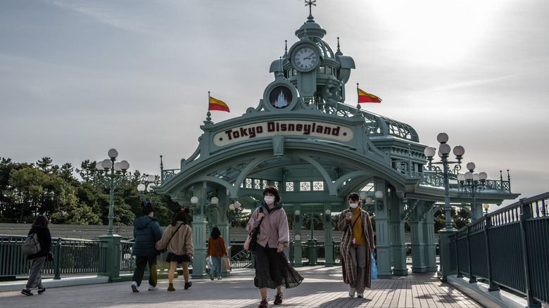 People pass beneath the entry archway leading to Tokyo Disneyland