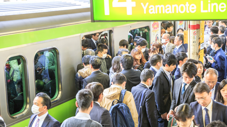 Crowd of commuters ascends and drops from train at rush hour in Shinjuku Station, Tokyo's main station.
