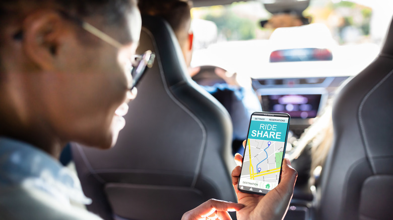 African American woman using a ride share app in the backseat of a car