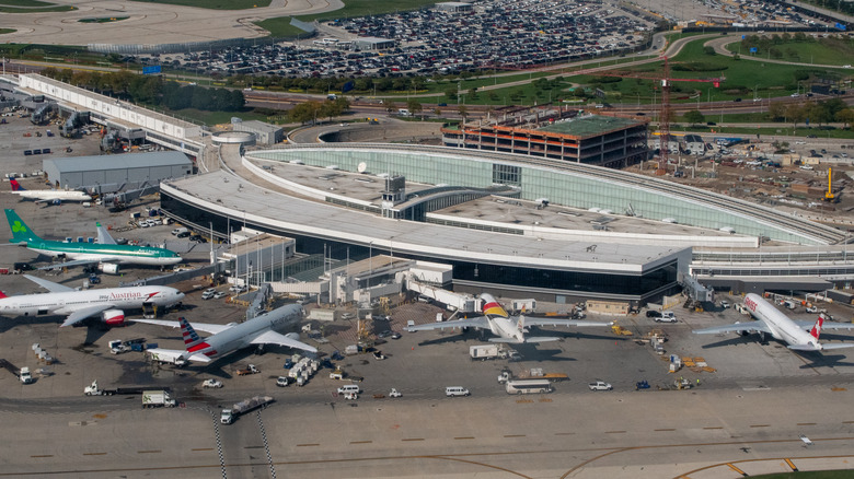 Aerial view of Chicago O'Hare Airport's Terminal 5. Several airplanes from different airlines are parked at the gates.