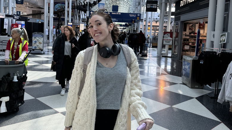 Brunette woman pausing to take a photo while rushing to make a connection at O'Hare International Airport, Chicago