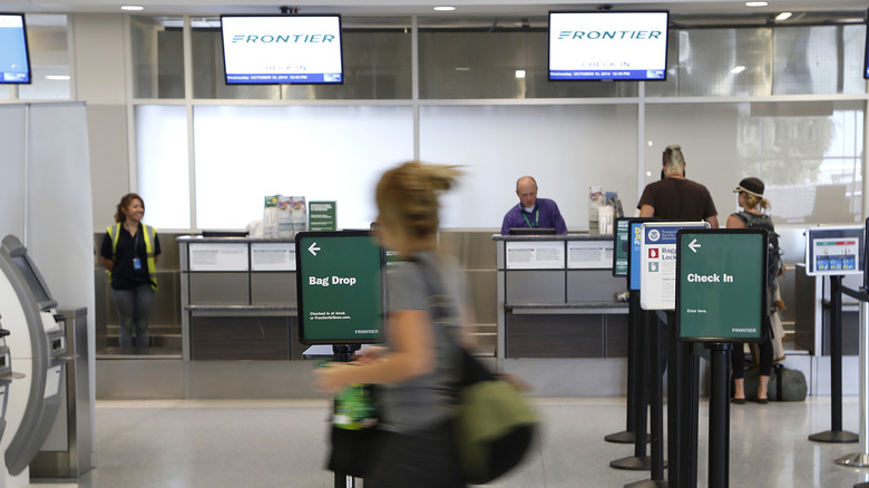 People check in at the desk for Frontier Airlines in Terminal E at Dallas/Fort Worth