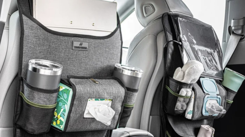 Close-up view of two grey Trekterra seat back organizers in a car filled with wipes, cups, gloves, and other travel essentials