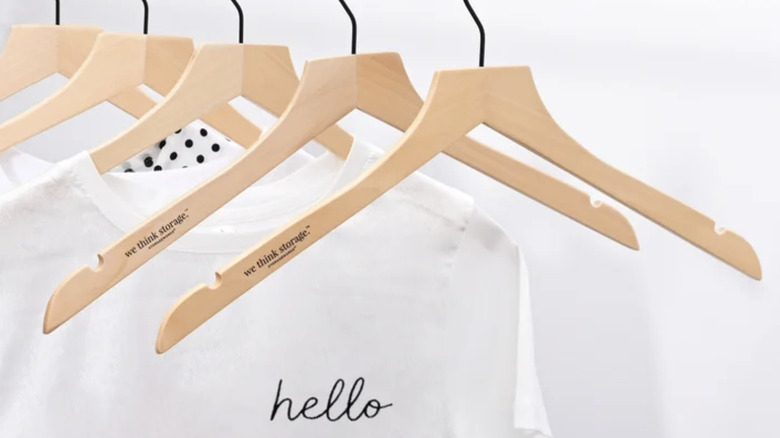 Close-up view of WeThinkStorage slim wood hangers with a white t-shirt that reads "hello"