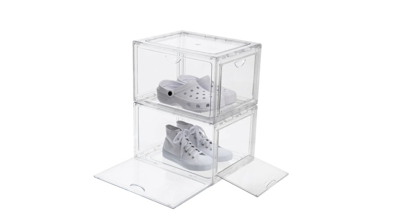 Set of two clear acrylic stackable storage boxes with shoes inside of them on stark white background