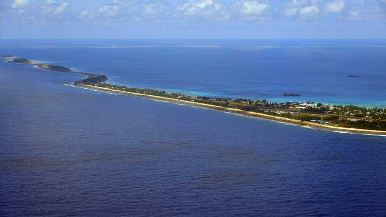 View of Funafuti Atoll, Tuvalu, with blue water surrounding a sparsely developed strip of land
