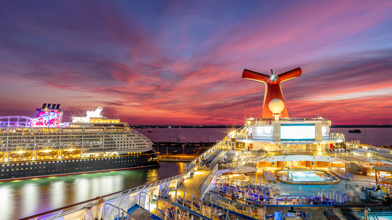 Port Canaveral, Florida, USA - September 5, 2019: Carnival Liberty and Disney Dream cruise ships docked in Port Canaveral at sunset. Beautiful red-orange-blue sunset sky in the background.