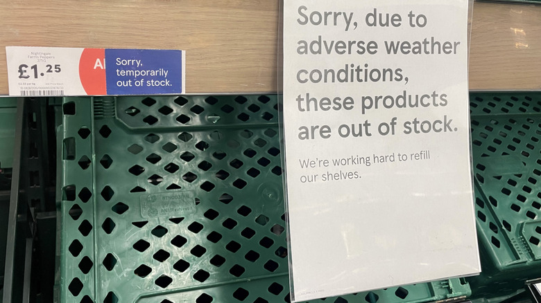 Empty shelves with a sign explaining shortage due to weather in England grocery
