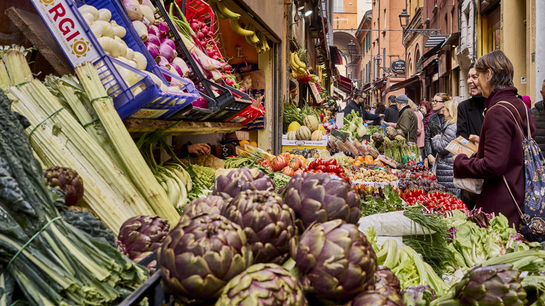 Local market in Bologna, Italy showing fresh produce and people shopping
