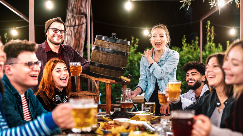 Happy men and women having fun drinking out at beer garden