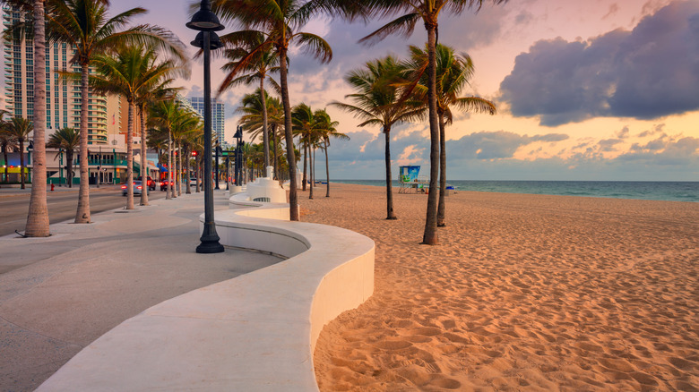 Sandy beach in Fort Lauderdale, Florida, with a curved walkway on left side at golden hour
