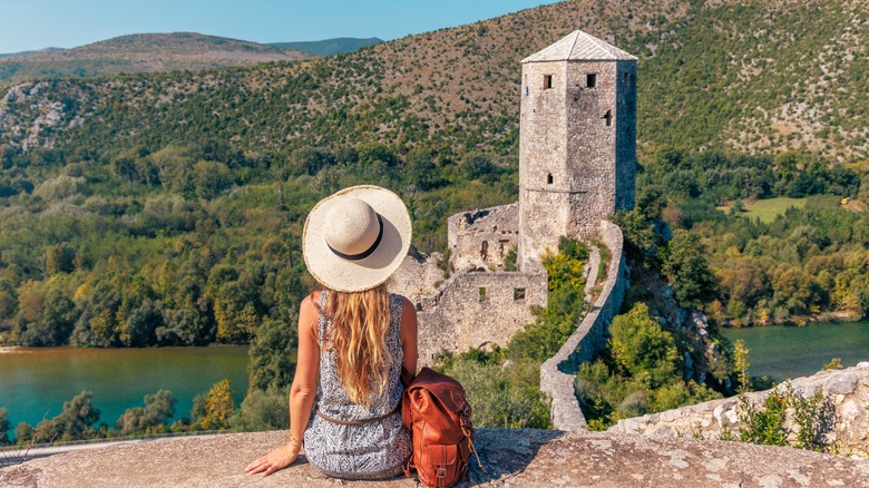 Woman in white hat sits on overlook
