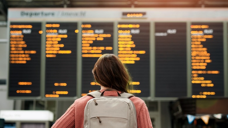 Woman with backpack looking at departures board