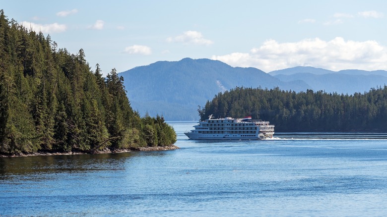 Cruise ship traveling between forested islands