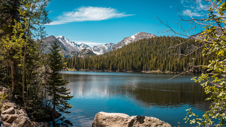 Bear Lake reflecting snow-capped mountain under a blue sky in Rocky Mountain National Park.
